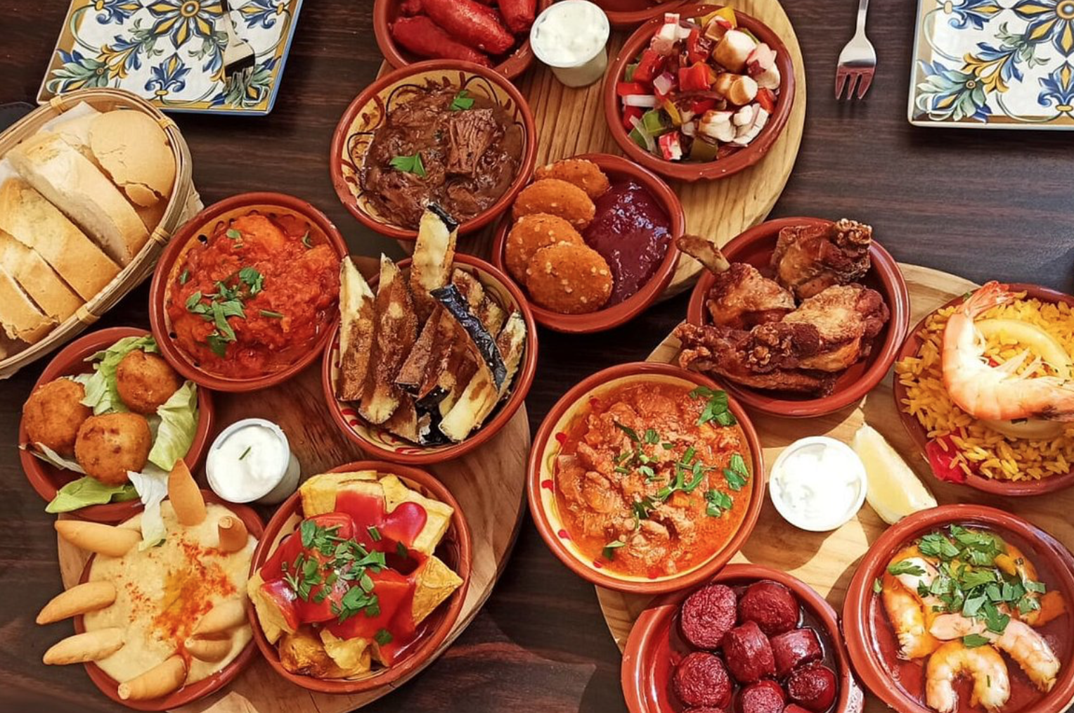 Mesa de tapas andaluzas con aceitunas, embutidos y una copa de vino local sobre madera